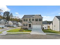 A charming two-story home features a well-maintained lawn, a driveway, and classic curb appeal in a suburban neighborhood at 1316 Village Brook Drive, Dacula, GA 30019