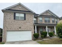 Two-story brick home featuring a two-car garage, covered front porch, and neatly trimmed landscaping at 7328 Vigo Dr, Lithonia, GA 30058