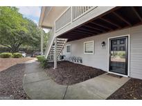 Apartment exterior with gray siding, black door, wood staircase, and trimmed mulch area at 105 Olde Mill Ln, Norcross, GA 30093