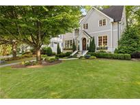 Beautiful home featuring a lush green lawn, mature tree, manicured landscaping, and a charming gray exterior at 1201 Beech Valley Ne Rd, Atlanta, GA 30306