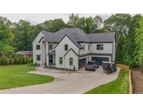 Stunning white modern house featuring black trim, three car garage, and large driveway at 2977 N Bogan Rd, Buford, GA 30519