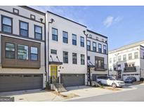 Modern townhome with a yellow front door, gray garage door, and beautiful architectural details at 1149 Ansel Nw Ln, Atlanta, GA 30318