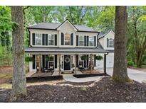 Charming two-story home featuring a beautifully landscaped yard and inviting front porch with rocking chairs at 6520 Glen Pond Trce, Cumming, GA 30028