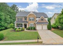 Beautiful two-story home featuring a stone facade, manicured lawn, and attached two car garage at 134 Johnston Farm Ln, Woodstock, GA 30188