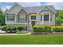 Charming two-story home with well-manicured lawn and lovely landscaping and a combination of light and medium gray siding at 2180 Oakpointe Ct, Buford, GA 30519