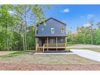 Two story house exterior with new driveway, a wooden porch and mature trees in the back at 70 Wheeler Lake Path, Dallas, GA 30157