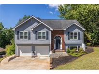 Charming two-story home featuring a well-manicured lawn, two-car garage, and inviting front entrance with tasteful landscaping at 1215 Smoke Hill Ln, Hoschton, GA 30548