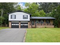 Charming split-level home features a brick facade, a covered porch, and a two-car garage at 382 Plantation Blvd, Lawrenceville, GA 30046