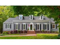 Charming single-Gathering home with gray siding, dormer windows, manicured landscaping, and a brick walkway to the front door at 6800 Wright Rd, Atlanta, GA 30328
