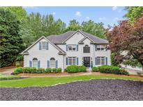 Charming two-story home features a well-manicured lawn, beautiful landscaping, and classic architectural details at 220 Foxley Way, Roswell, GA 30075