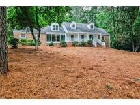 Charming home with a brick facade, dormer windows, covered porch, and a large, wooded front yard at 2244 Deer Ridge Dr, Tucker, GA 30087