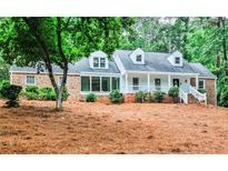 Charming brick and white home with dormer windows and inviting front porch with a landscaped yard at 2244 Deer Ridge Dr, Tucker, GA 30087
