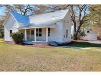 Charming white home with a metal roof, inviting front porch, and well-maintained lawn at 6316 Rockland Rd, Lithonia, GA 30038