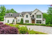 Stunning white exterior with beautiful landscaping and a circular driveway at 1285 Stuart Rdg, Johns Creek, GA 30022