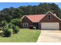 Charming brick home with an attached garage and a well-manicured front yard, nestled beneath a clear blue sky at 75 Oak Hill Dr, Covington, GA 30016