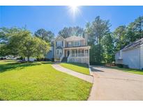 Charming two-story home with landscaped yard and a welcoming front porch with green grass and blue skies at 12237 Cypress Ln, Fayetteville, GA 30215