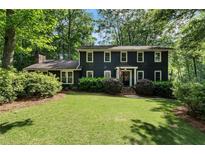 Charming two-story home with a lush green lawn and mature trees creating a serene setting at 1435 Withmere Ln, Atlanta, GA 30338