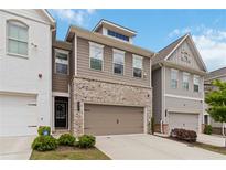 Charming townhome features a two-car garage, a mix of brick and siding, and manicured landscaping at 1227 Herty Dr, Marietta, GA 30062