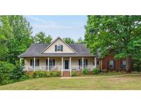 Charming home with a covered front porch, green lawn, and mature trees around the property at 418 Whisper Wood Way, Locust Grove, GA 30248