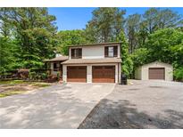 Charming two-story home boasts a two car garage and separate additional garage, surrounded by lush trees and a generous driveway at 466 Victoria Rd, Woodstock, GA 30189