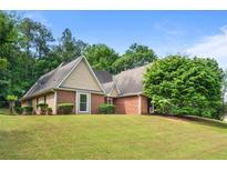 Charming single-story home featuring a brick and tan siding exterior with a well-maintained lawn and mature trees at 221 The Esplanade Se Way, Loganville, GA 30052