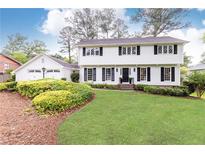 Charming white two-story home with a well-manicured lawn, mature landscaping, and an attached two-car garage at 2730 Burtz Dr, Marietta, GA 30068