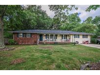 Charming single-story home with a brick accent and welcoming front porch, surrounded by mature trees and a lush green lawn at 8053 Duralee Ln, Douglasville, GA 30134