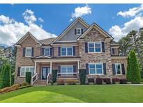 Elegant two-story home with a combination brick and stone facade, manicured lawn, and mature landscaping at 859 Heritage Lake Way, Grayson, GA 30017