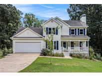Charming two-story home featuring a manicured lawn, attached garage, and inviting front porch at 7155 Bannister Park Ln, Cumming, GA 30028