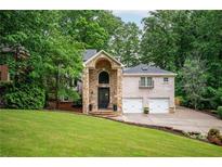 Beautiful brick home featuring an arched stone entryway, two car garage, and a well manicured front yard at 3290 Coachmans Ne Way, Roswell, GA 30075