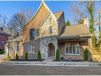 Charming brick and stone home featuring an arched entryway, manicured landscaping, and a classic architectural design at 580 Cliftwood Ct, Sandy Springs, GA 30328
