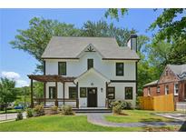 Charming two-story home with a manicured lawn, stone walkway, and a lovely pergola covered porch at 1059 Woodland Ave, Atlanta, GA 30316