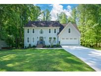 Charming home with a manicured lawn, gray stucco, blue front door, and a two-car garage at 3295 Waters Ml, Alpharetta, GA 30022