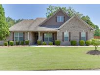 Charming brick home with a well-manicured front yard, lush green grass, and mature landscaping at 2906 Jones Phillips Rd, Dacula, GA 30019