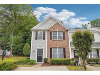 Charming two-story townhome featuring brick and gray siding, complemented by manicured landscaping and black shutters at 9165 Nesbit Ferry Rd # 9, Alpharetta, GA 30022