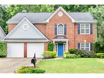 Charming brick home featuring a manicured lawn, blue door, and a two-car garage at 3168 Kirkwood Nw Dr, Kennesaw, GA 30144