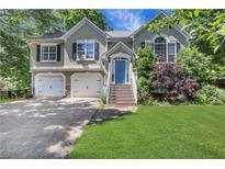 Charming two-story home with a well-manicured lawn, a blue front door, and a two-car garage at 3820 Pheasant Run Trce, Cumming, GA 30028