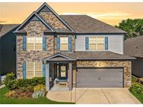 Beautiful two-story home with stone and brick facade, gray garage door and blue shutters at 408 Honeybee Ln, Canton, GA 30115