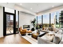 Bright living room with hardwood floors, modern furniture, fireplace, and floor to ceiling windows with city views at 40 12Th Ne St # 1406, Atlanta, GA 30309