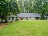 Charming single-story home with a lush green lawn and a welcoming red front door at 4708 Tall Pines Nw Dr, Atlanta, GA 30327