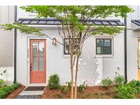 Charming white brick home with a vibrant salmon-colored front door, complemented by a well-manicured yard at 4462 Dandelion Ln, Atlanta, GA 30342