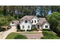 Inviting two-story traditional home featuring a manicured lawn, mature trees, and a three car garage at 122 Griffin Way, Canton, GA 30115