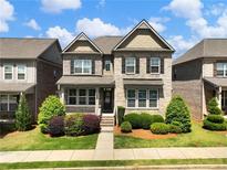Charming two-story home with stone accents, manicured lawn, and mature landscaping at 4905 Sterling Close, Buford, GA 30518