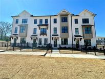 Beautiful, modern townhouse exterior with black trim, white brick, black iron fence, and manicured landscaping at 508 Healy Dr # 70, Cumming, GA 30040
