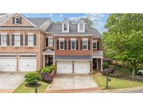 Beautiful brick townhome featuring a two-car garage, manicured landscaping, and a classic architectural design at 11945 Dancliff Trce, Alpharetta, GA 30009