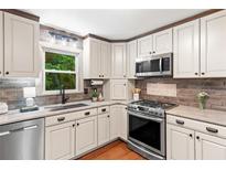 A kitchen featuring modern appliances, light cabinets, and wood flooring at 211 Caboose Ln, Woodstock, GA 30189