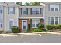 Inviting townhouse featuring a brick facade, green shutters and door, complemented by lush landscaping at 1295 Kilmington Ct, Alpharetta, GA 30009