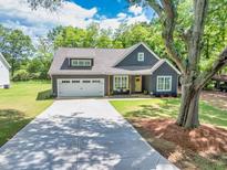 Charming single-story home featuring a well-manicured lawn, gray siding, and a two-car garage at 399 Chestnut St, Social Circle, GA 30025