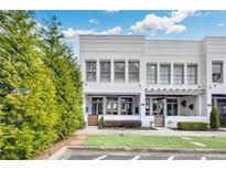 Charming two-story townhome with white painted brick, manicured lawn and landscaped garden at 212 Sessions St, Woodstock, GA 30188