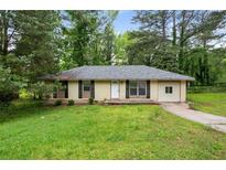 Charming single-story home with black shutters and well-maintained front yard and mature trees at 8169 Kendrick Rd, Jonesboro, GA 30238